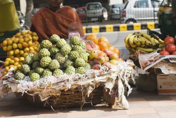 Female vendor selling fruits at a market stall, New Delhi, India