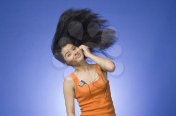 Young woman listening an MP3 player against blue background