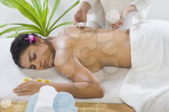 Massage therapist applying massage cream on a young woman's back