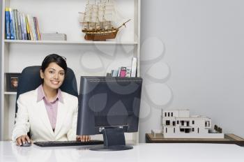 Portrait of a businesswoman working on a desktop PC in an office