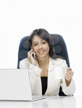 Businesswoman talking on a mobile phone and holding a coffee mug