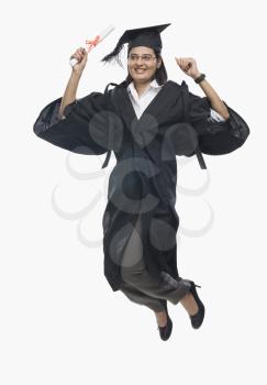 Woman jumping with her diploma in graduation gown 