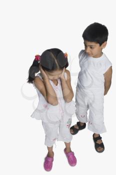 Girl covering her ears while her brother talking
