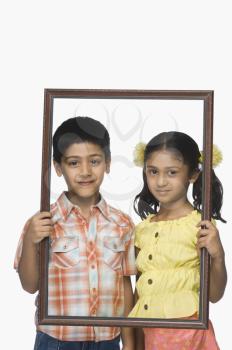 Portrait of a boy and a girl holding an empty picture frame