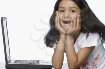 Portrait of a girl sitting in front of a laptop in shock