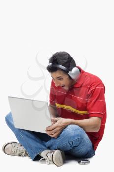 Man listening to headphones while using a laptop