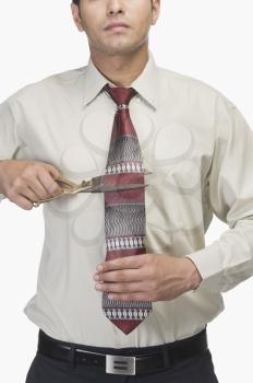 Businessman cutting his tie by scissors