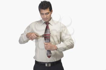 Businessman cutting his tie by scissors