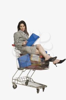 Businesswoman sitting in a shopping cart with files
