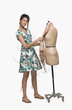 Female fashion designer trying a dress on a mannequin