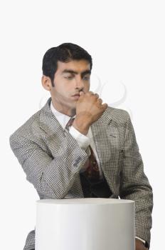 Businessman leaning on a wooden stand and thinking