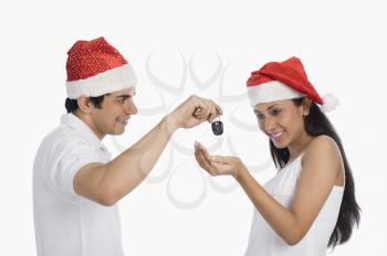 Man giving car key as a Christmas present to his girlfriend