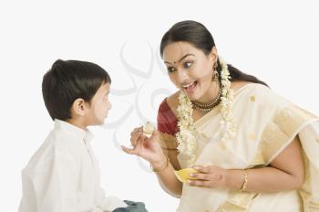 Woman feeding sweet to her son