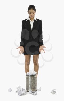 Businesswoman standing in front of a wastepaper basket and gesturing