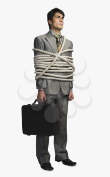 Businessman tied up with ropes and holding a briefcase