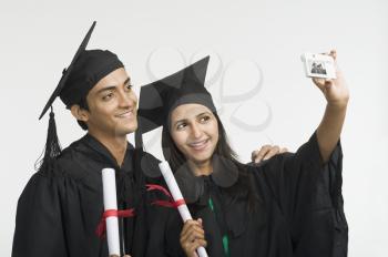 Couple in graduation gown taking a picture of themselves