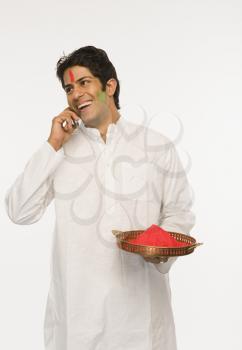 Man holding Holi colors and talking on a mobile phone