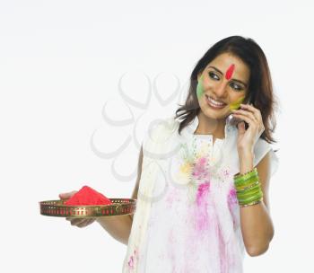 Woman holding Holi colors and talking on a mobile phone