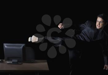 Frustrated businessman kicking a desktop pc