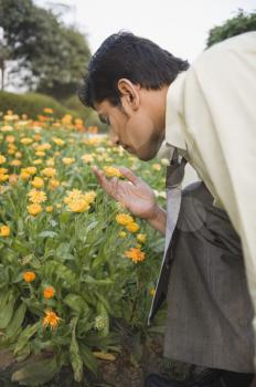 Businessman smelling flowers in a garden