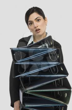Businesswoman holding stack of binders