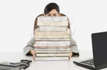 Businesswoman hiding behind a stack of books