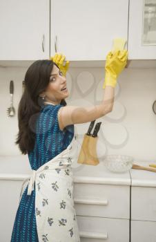 Woman cleaning a kitchen cabinet with a sponge