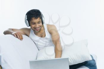 Man using a laptop and listening to headphones