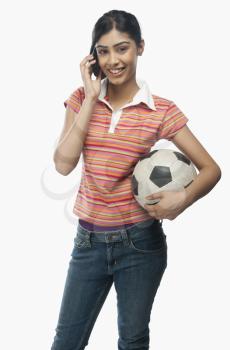 Woman talking on a mobile phone and holding a soccer ball