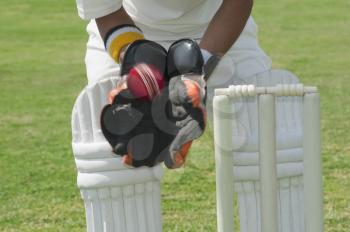 Wicket keeper standing behind stumps and catching a ball