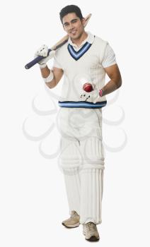 Portrait of a cricket batsman holding a bat and a ball