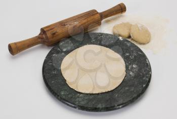Close-up of a rolling pin and a board with chapatti (Indian flatbread) and dough