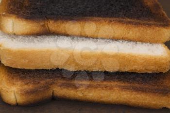 Slice of a bread between two burnt toasts