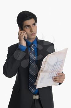 Real estate agent holding a blueprint and talking on a mobile phone