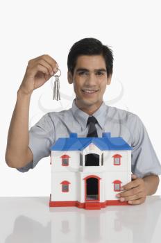 Real estate agent holding keys and a model home