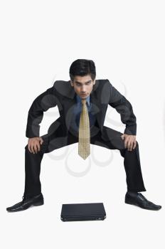 Businessman crouching in front of a laptop