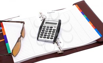 Open notebook glasses and a calculator on a white background.                   