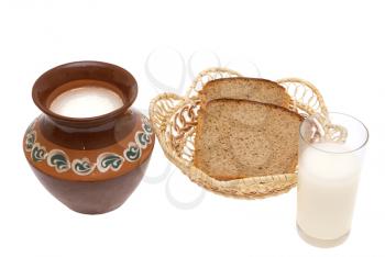 Milk in a jug and a glass, black bread in a wattled plate on a white background.                    