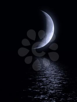 Half of moon in the dark blue sky over water