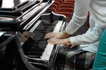 The music teacher shows the student how to play the piano.