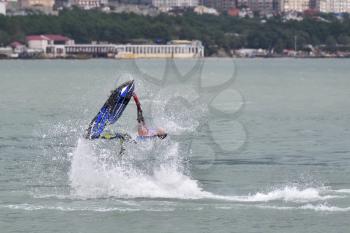 Young athlete guy doing flips on a jet ski in the sea