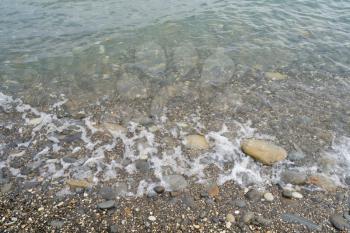 Transparent water of the Black Sea on the shore with small stones.