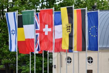 Flags of different countries in the park of the European city of Baden-Baden, Germany against the background of trees. Flags of the Commonwealth of Germany, Switzerland, France, America, England, Israel
