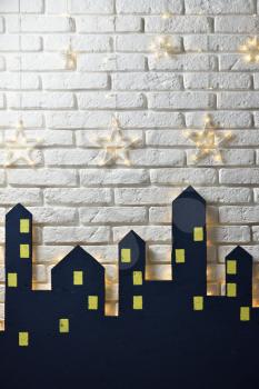 Decorations of the children's room for the New Year or Christmas, the silhouette of the city on a background of a white brick wall, place for text