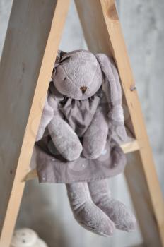 Children's soft toy rabbit sits on a wooden shelf