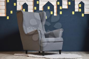 Furniture for a children's room a gray chair for home interior on a background of a white brick wall with a garland and the silhouette of the city