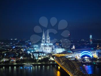 Night aerial view Koelner Dom Sankt Petrus (meaning St Peter Cathedral) gothic church and Hohenzollernbruecke (meaning Hohenzollern Bridge) crossing the river Rhein in Koeln, Germany