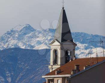 View of the city of Settimo Torinese, Italy with steple of St Peter in Chains church and the Alps mountains