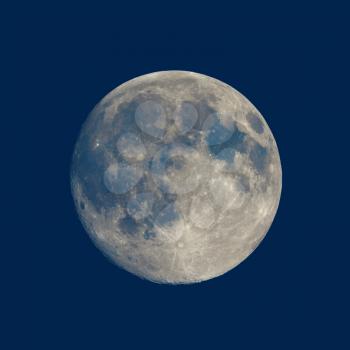 Full moon seen with an astronomical telescope over blue background