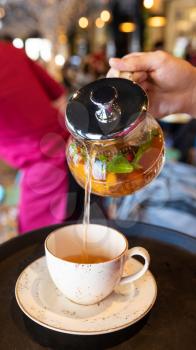 Pouring yellow natural tea to the cup